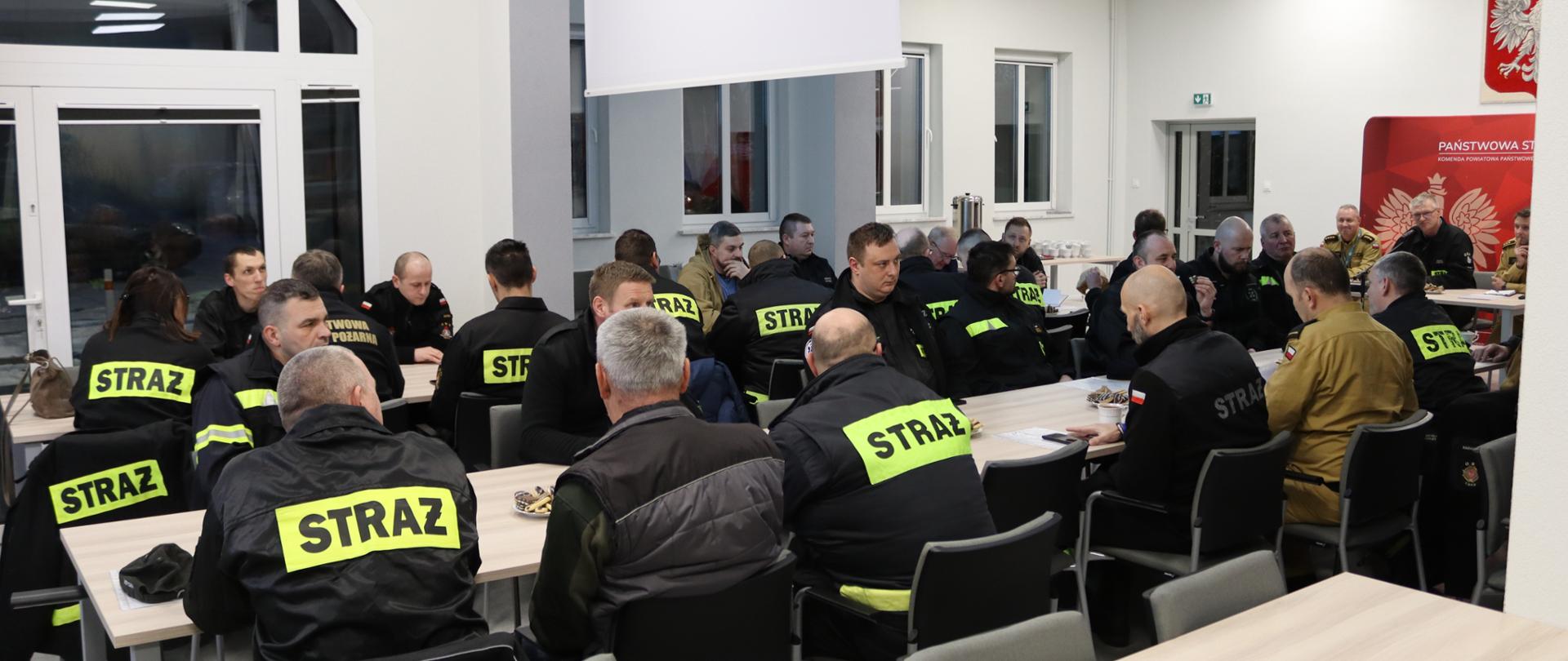 Na zdjęciu strażacy przy stole