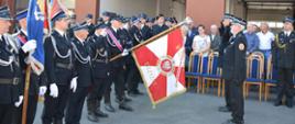 dwóch strażaków salutuje przed sztandarem