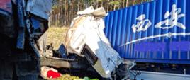 Zdjęcie przedstawia samochody ciężarowe po wypadku. Kabina jednego samochodu całkowicie zniszczona. 