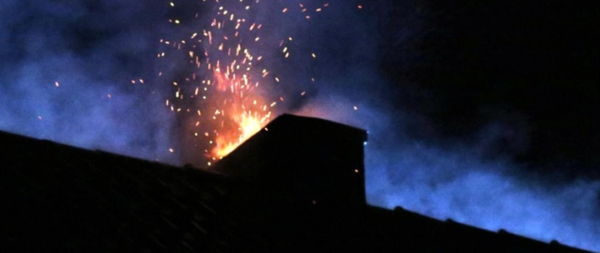 Płomienie oraz iskry wydobywające się z komina podczas pożaru sadzy. 