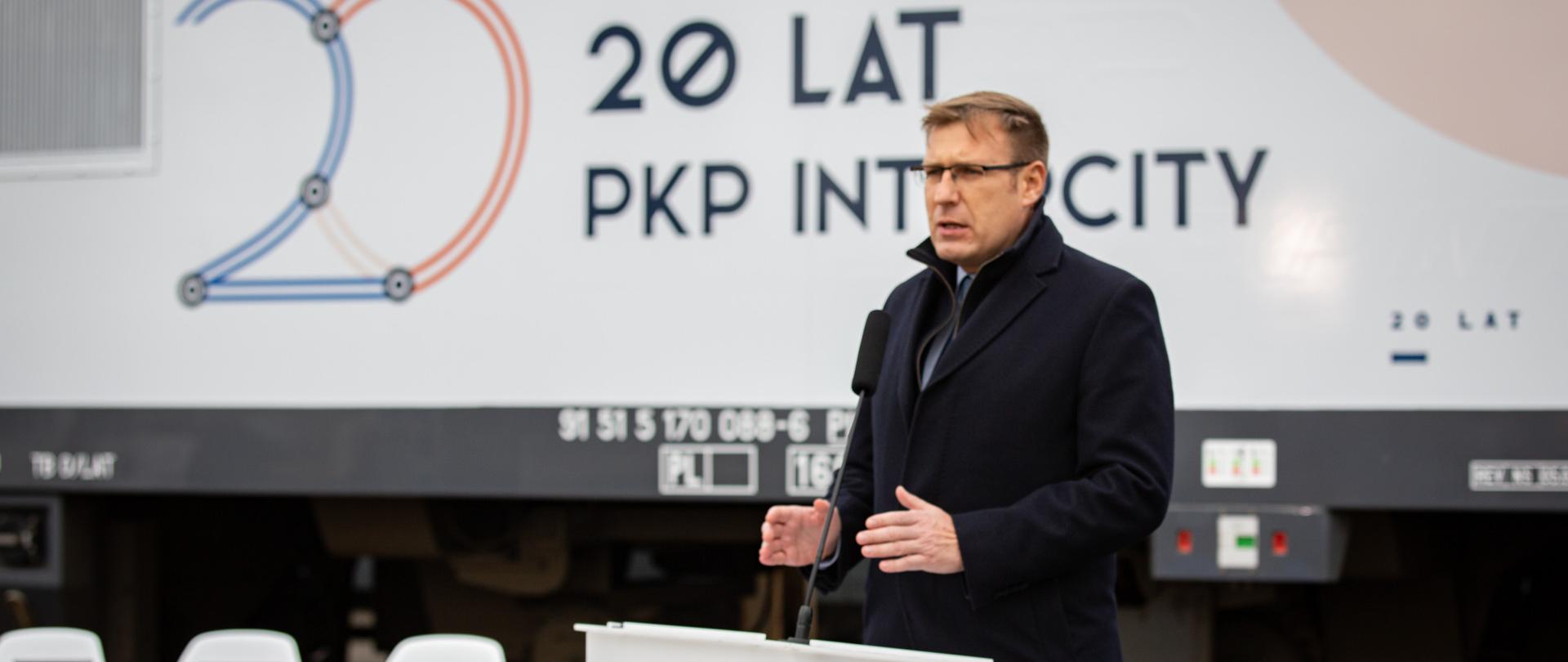 Wiceminister Maciej Małecki przemawia podczas uroczystości podpisania umowy PKP Intercity z NEWAG S.A. na dostawę nowych wielosystemowych lokomotyw. W tle baner z napisem 20 lat PKP Intercity.