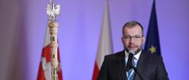 
Minister funduszy i polityki regionalnej Grzegorz Puda podczas spotkania z Konwentem Marszałków Województw RP, minister Puda stoi przy pulpicie i przemawia do mikrofonu
