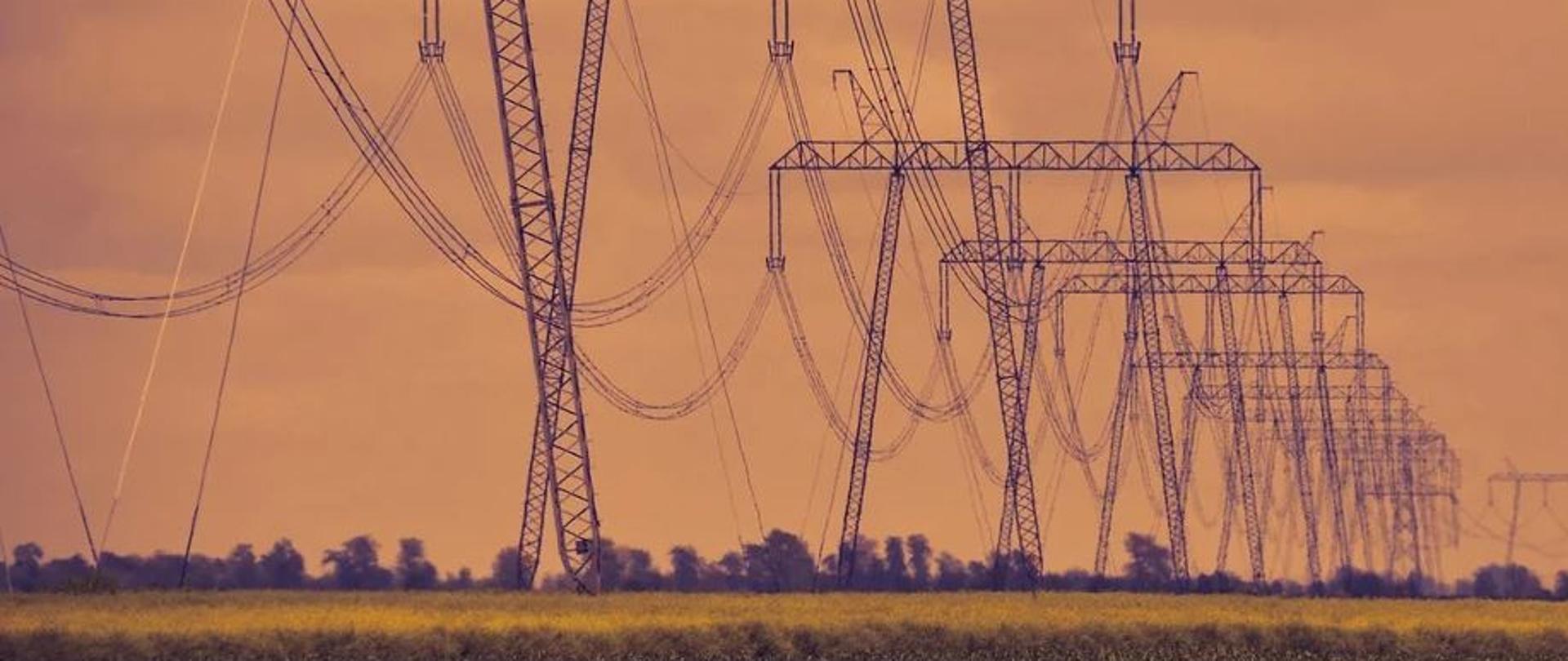 Zdjęcie pokazujące połączone kablami słupy wysokiego napięcia 