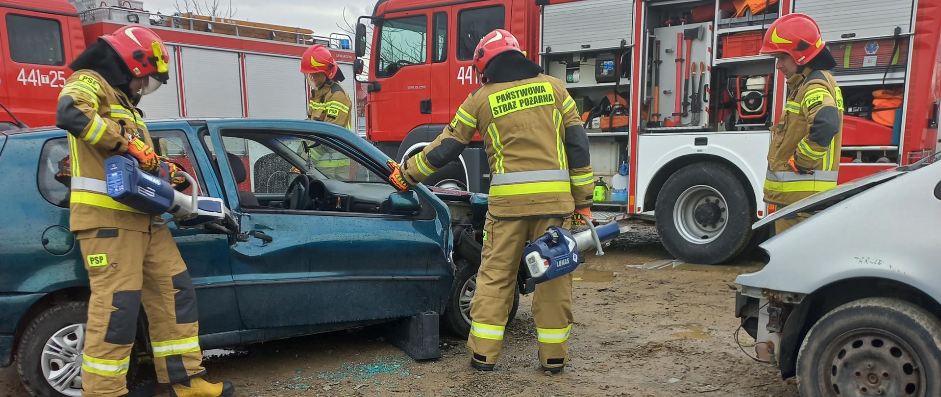 Zdjęcie przedstawia strażaków PSP ćwiczących techniki dostępu do osób poszkodowanych znajdujących się w samochodach. 