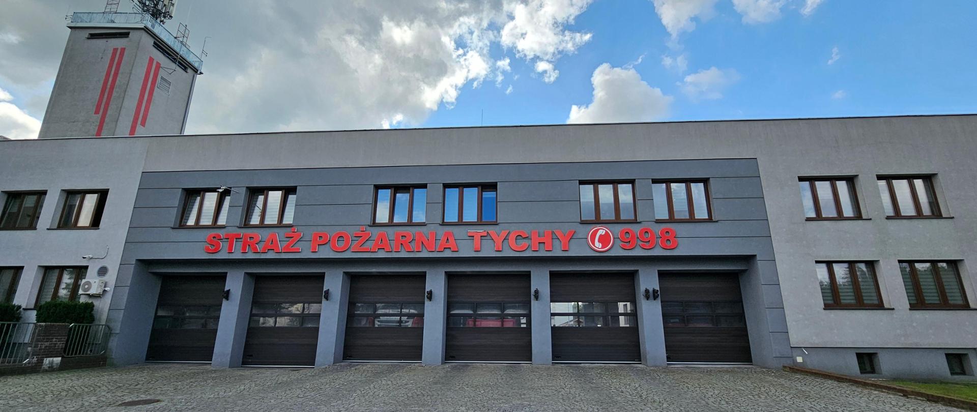 Budynek KM PSP w Tychach. Na nim napis czerwonego koloru STRAŻ POŻARNA TYCHY 998