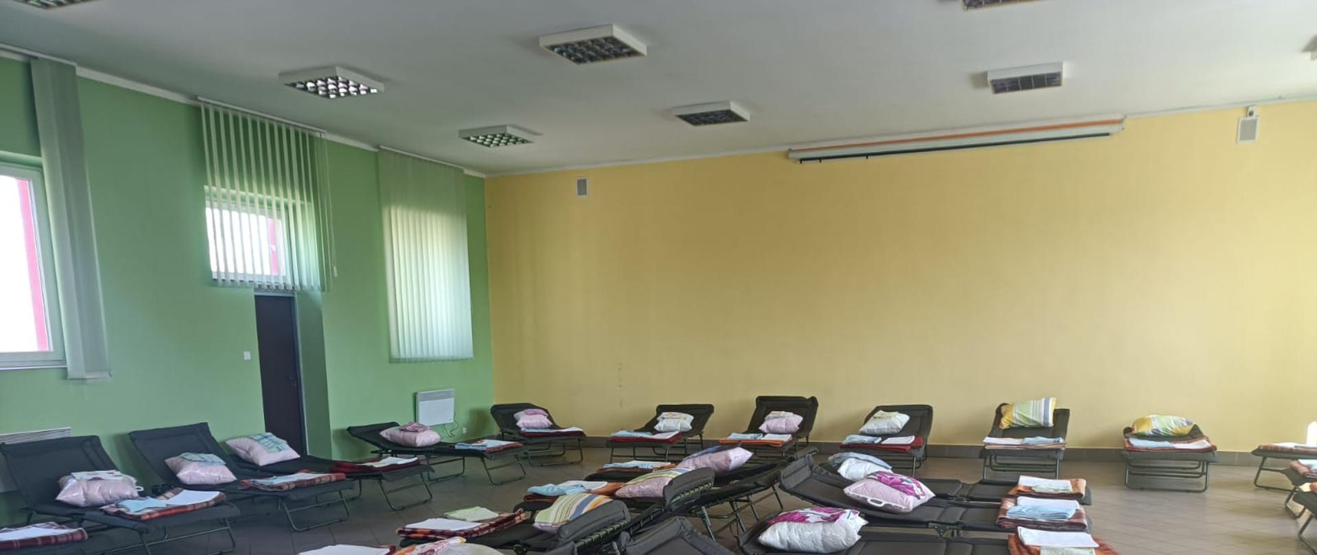 Przygotowane miejsca noclegowe w jednostce OSP. Na pierwszym planie rozstawione łóżka polowe.