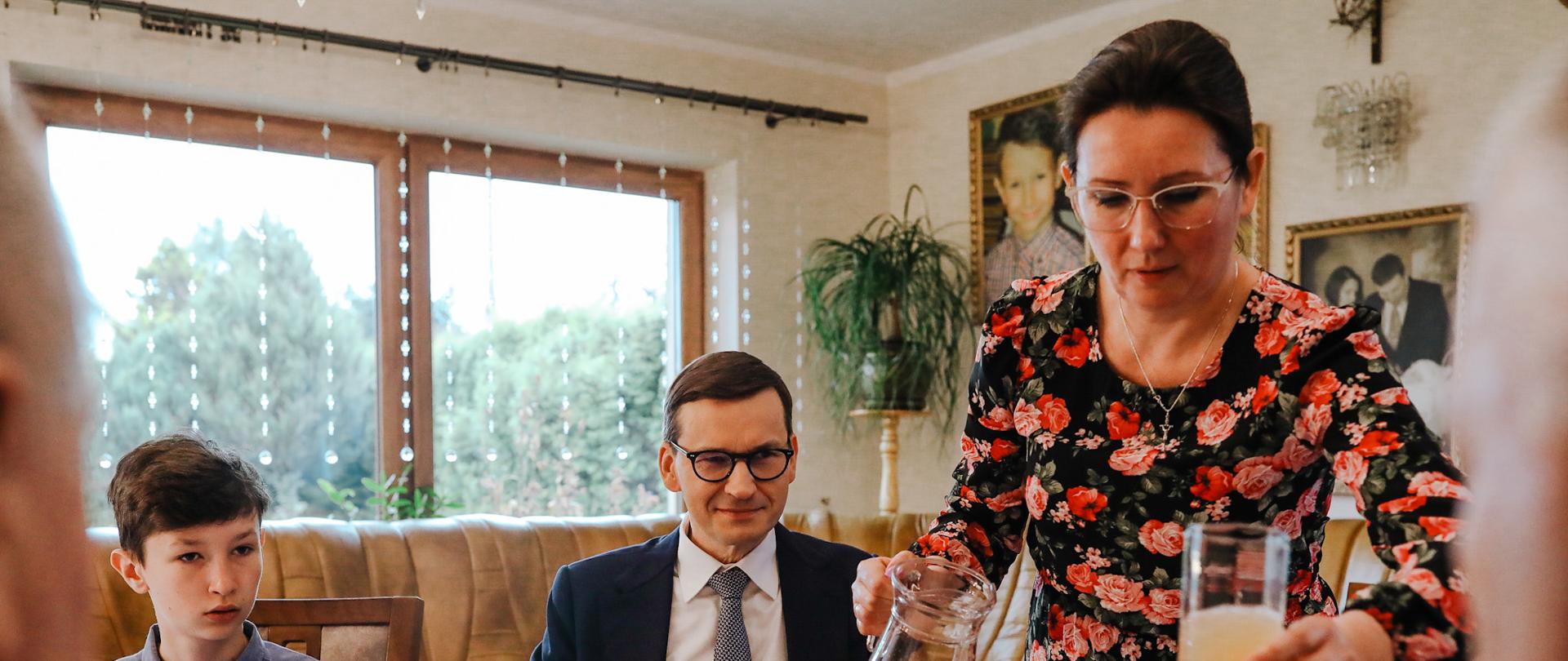 Premier siedzi przy stole.