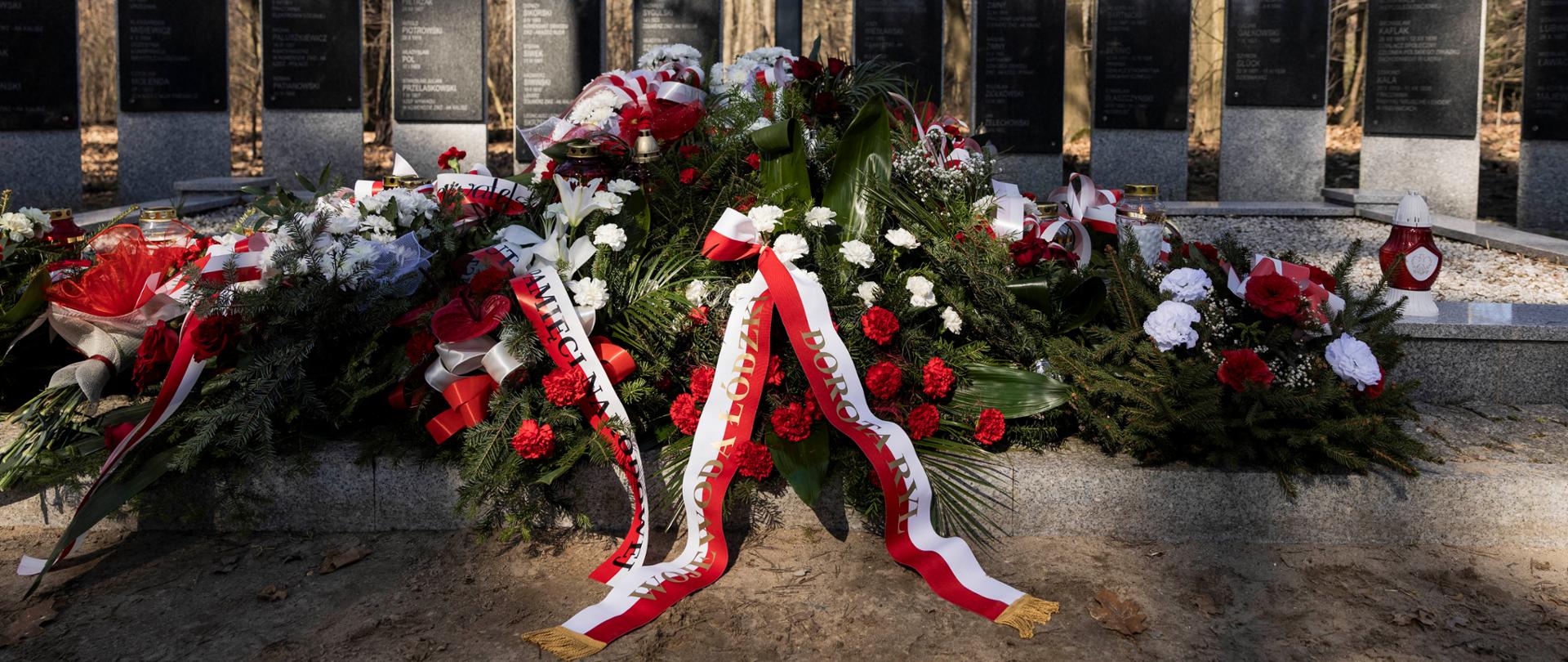 Kwiaty złożone pod pomnikiem w Lesie Lućmierskim 