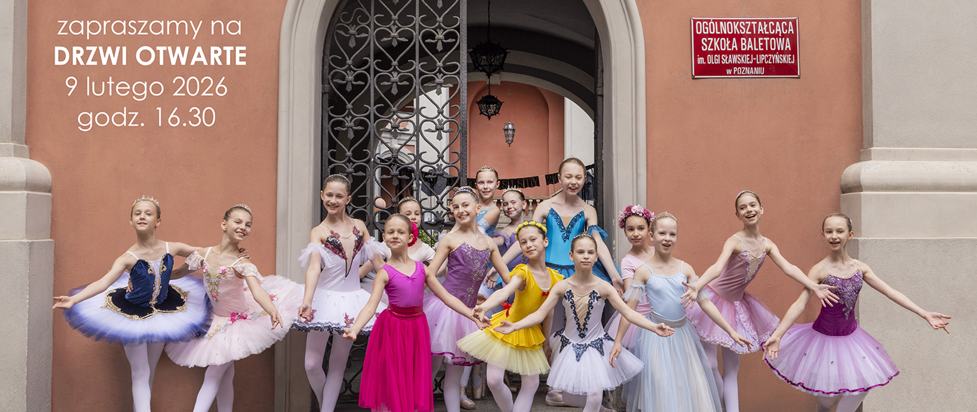 Grupa dzieci w kolorowych strojach na tle wejścia do szkoły