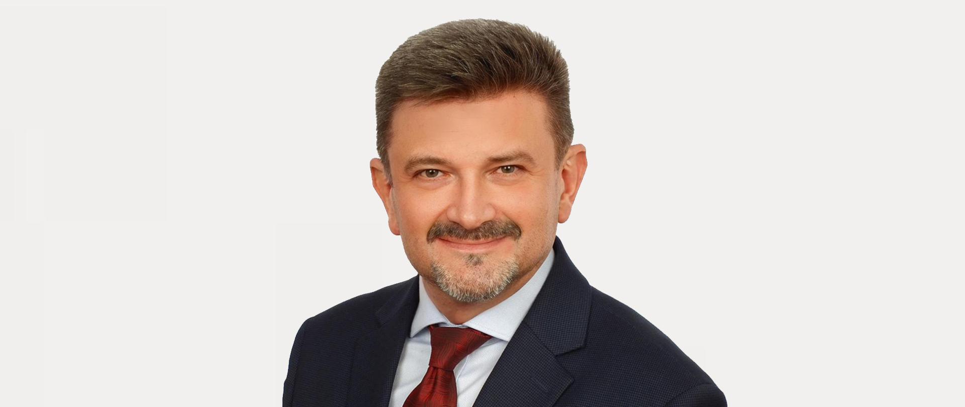 Wicewojewoda Piotr Pośpiech. Ubrany jest w granatowy garnitur. Ma na sobie białą koszulę razem z czerwonym krawatem. 