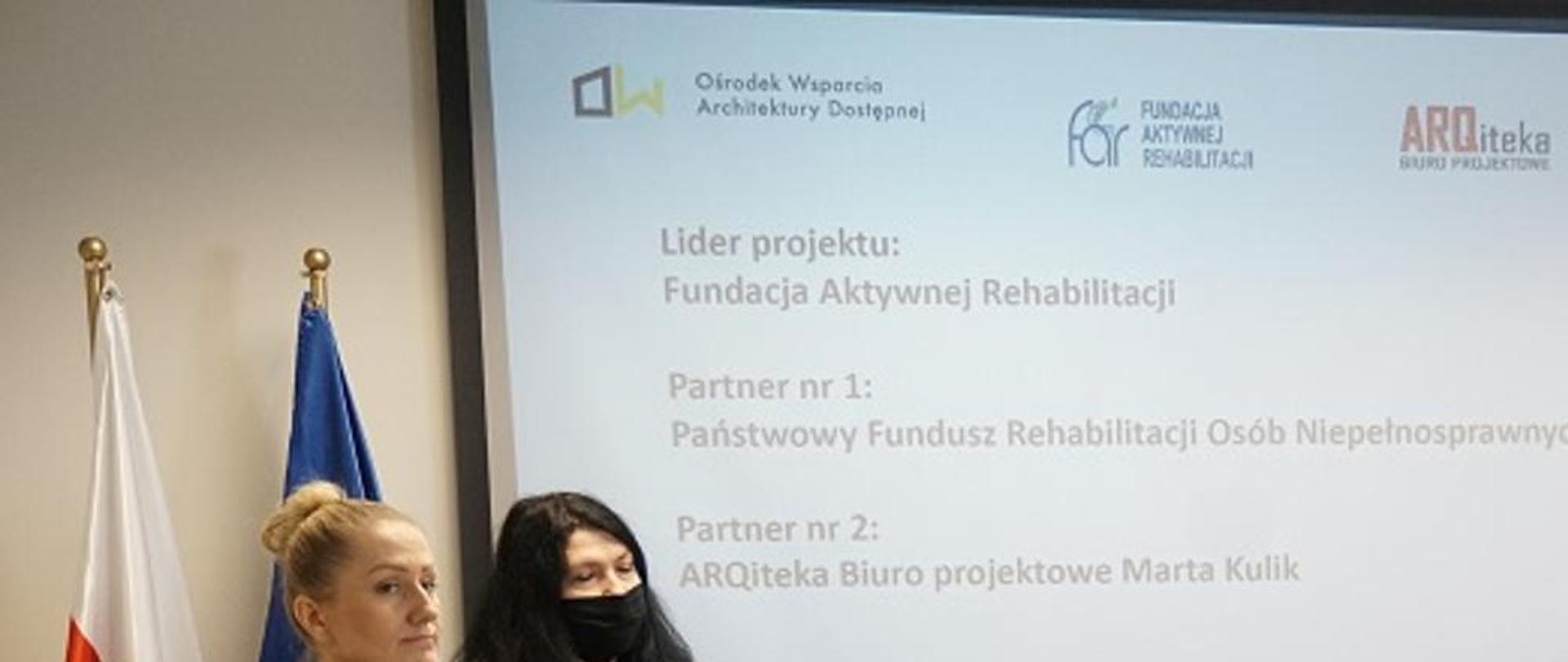 Na zdjęciu widoczne 6 osób: od lewej tłumaczka języka migowego, architekt Marta Kulik, na wózku inwalidzkim siedzi prezes Robert Jagodziński, obok stoi prezes PFRON Krzysztof Michalkiewicz, minister Małgorzata Jarosińska-Jedynak oraz minister Paweł Wdówik i jego pies przewodnik.