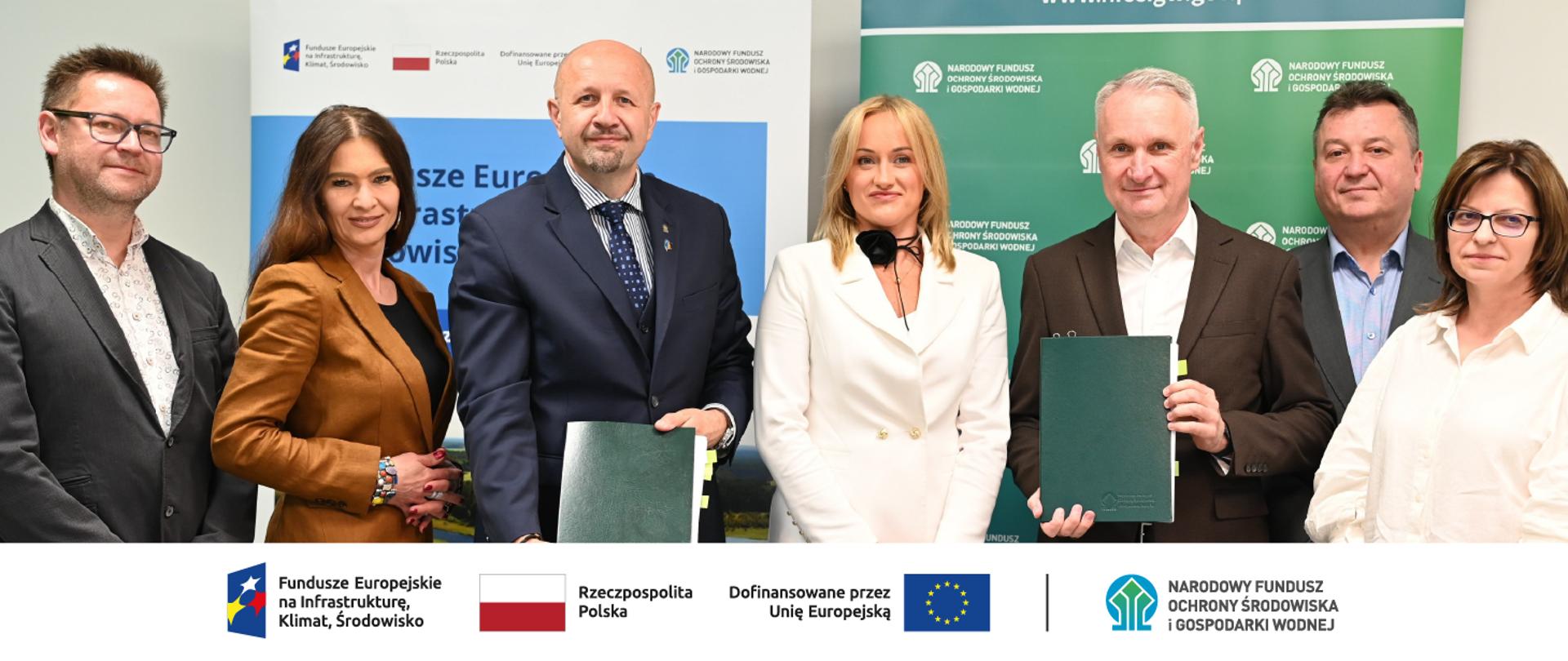 Zdjęcie grupowe. W stopce grafiki ciąg logotypów: Fundusze Europejskie na Infrastrukturę, Klimat, Środowisko, flaga Rzeczypospolita Polska, flaga UE i Dofinansowane przez UE, NFOŚiGW.