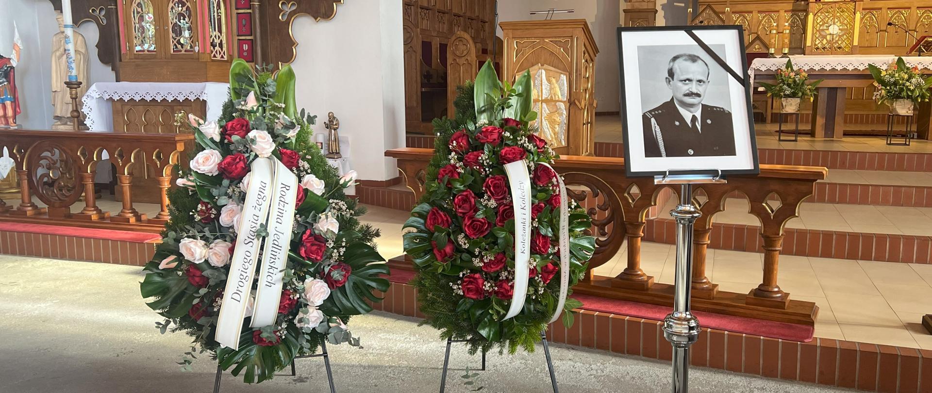 Zdjęcie zmarłego na tle ołtarza. Z lewej strony widoczne są wieńce. Zdjęcie powiększy się po kliknięciu na nie.