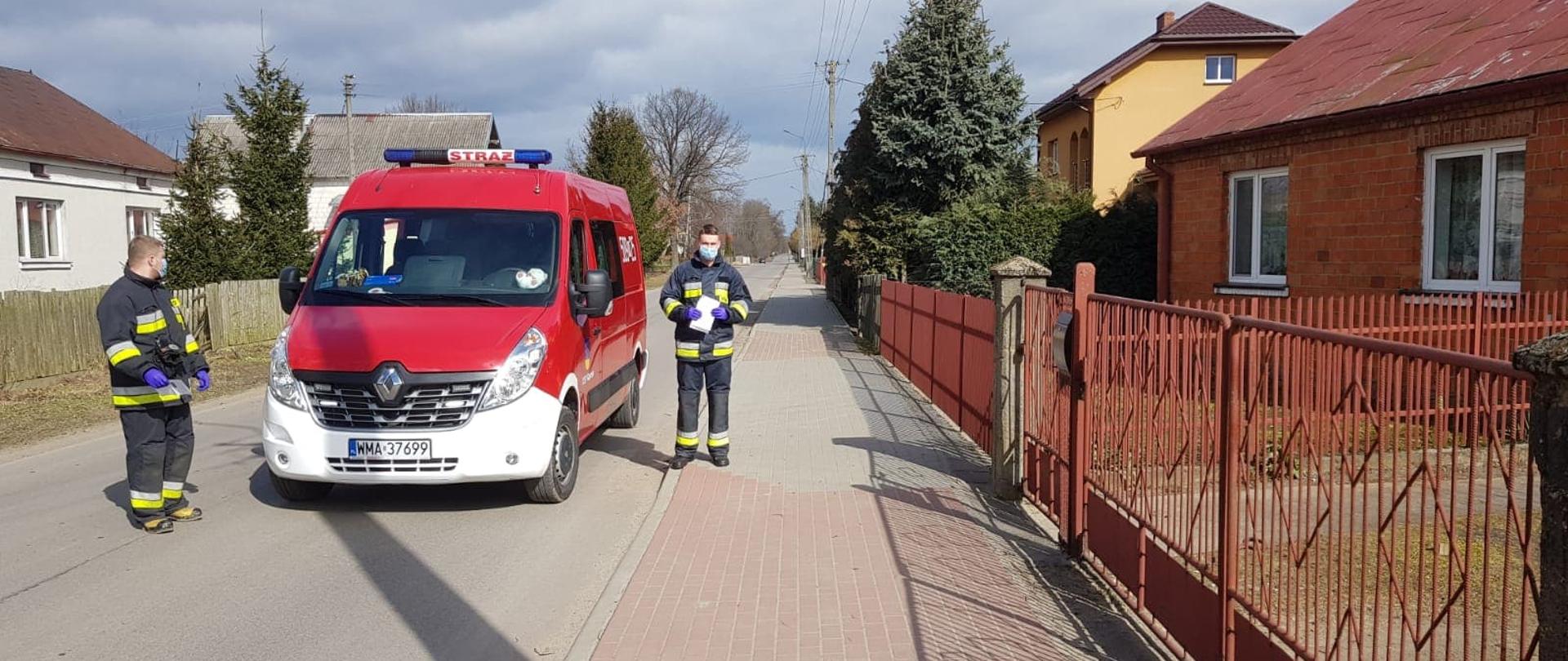 Dwóch strażaków OSP roznosi ulotki mieszkańcom.