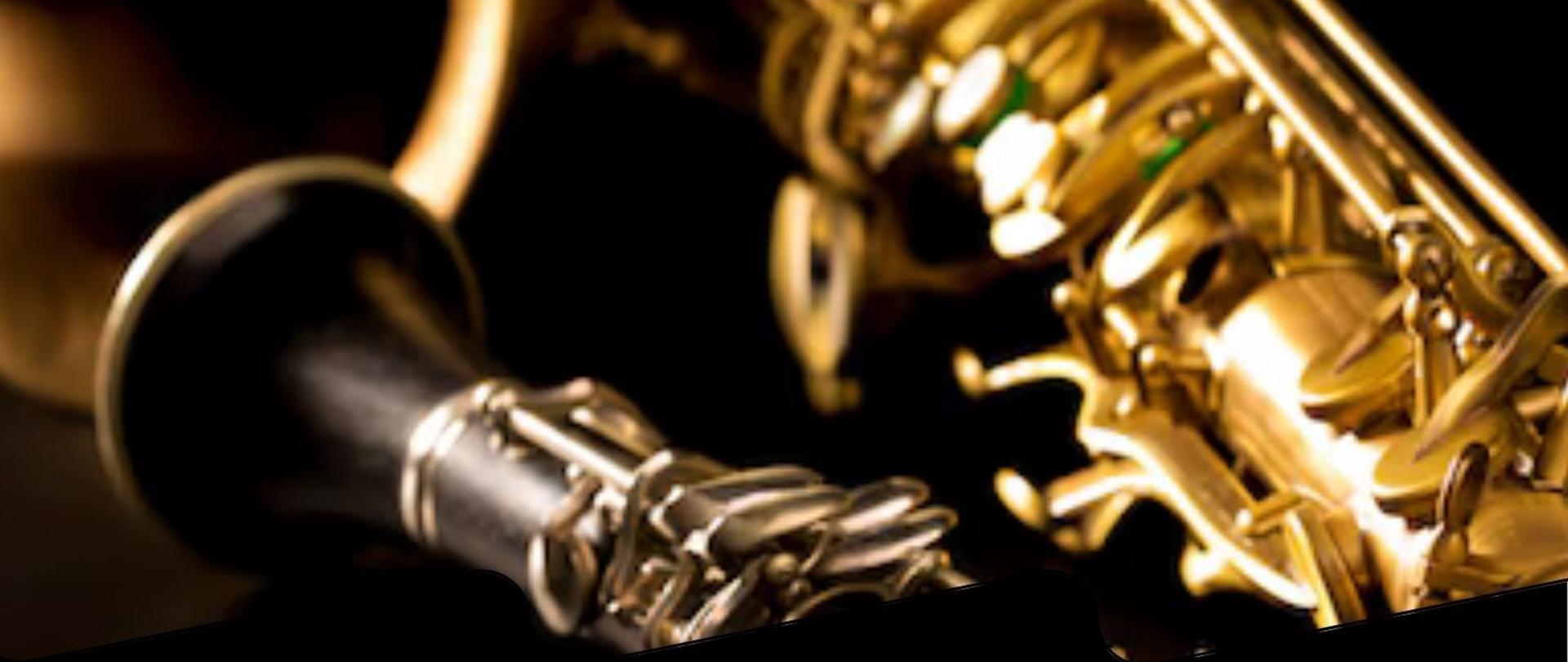 Plakat w pionie informujący o popisie uczniów klasy klarnetu i saksofonu, który odbędzie się 11 czerwca o godzinie 17:00. Głównym elementem plakatu jest zdjęcie saksofonu i klarnetu. Cały plakat w kolorystyce czerni. U dołu plakatu jasnymi listerami data i godzina wydarzenia.