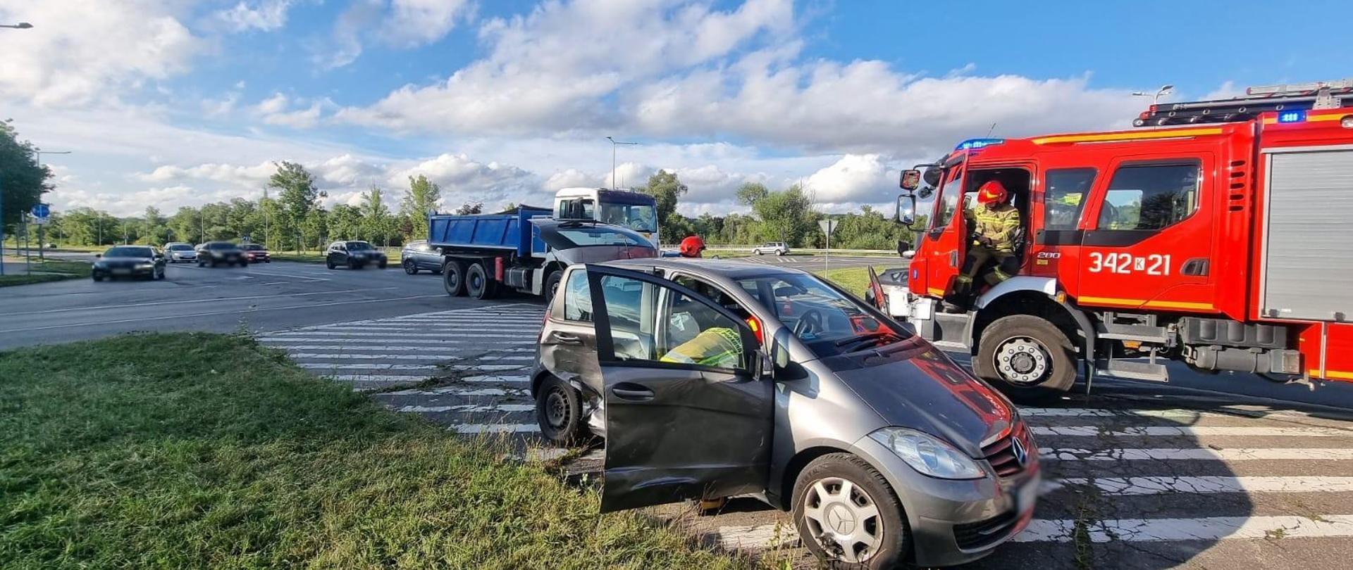 Uszkodzony samochód osobowy, a w tle samochód ciężarowy oraz pożarniczy