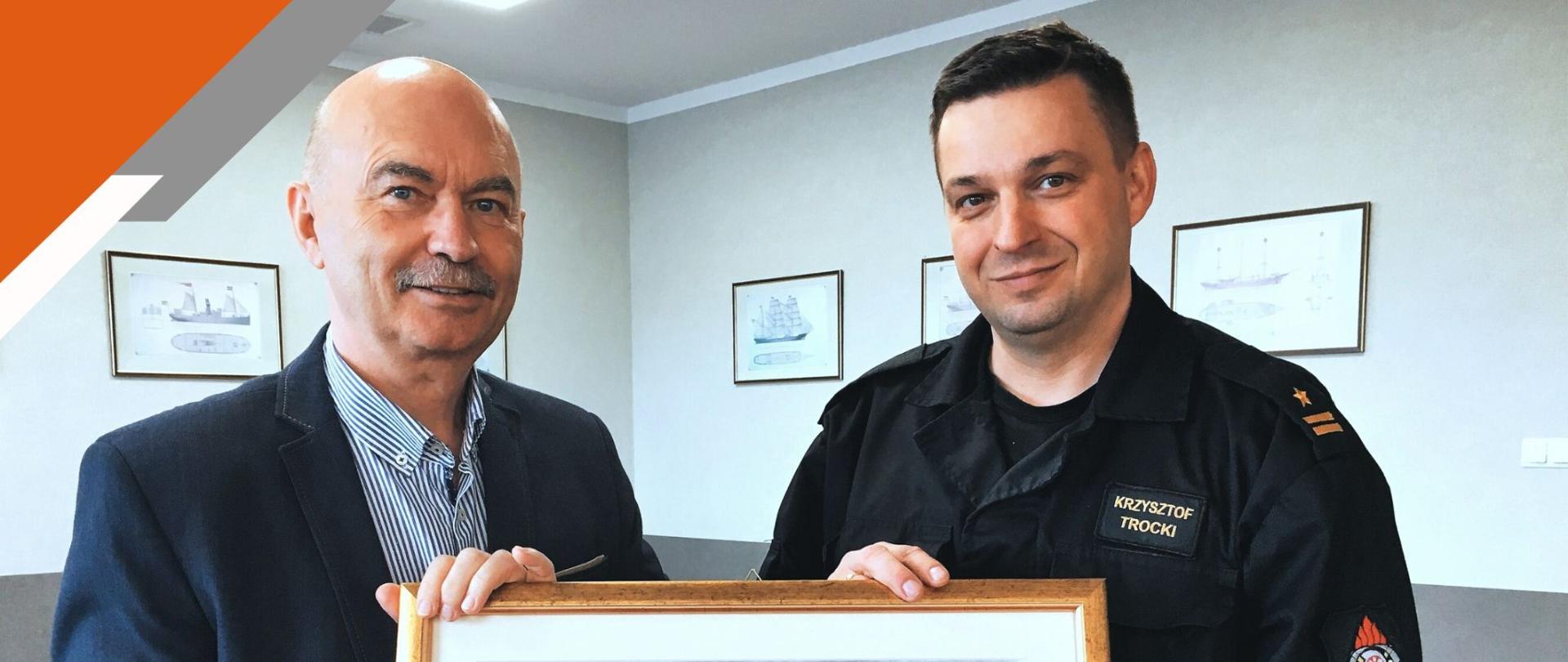 Zdjęcie przedstawia Komendanta Miejskiego wręczającego poddziekanie dla przedstawiciela firmy Markos.