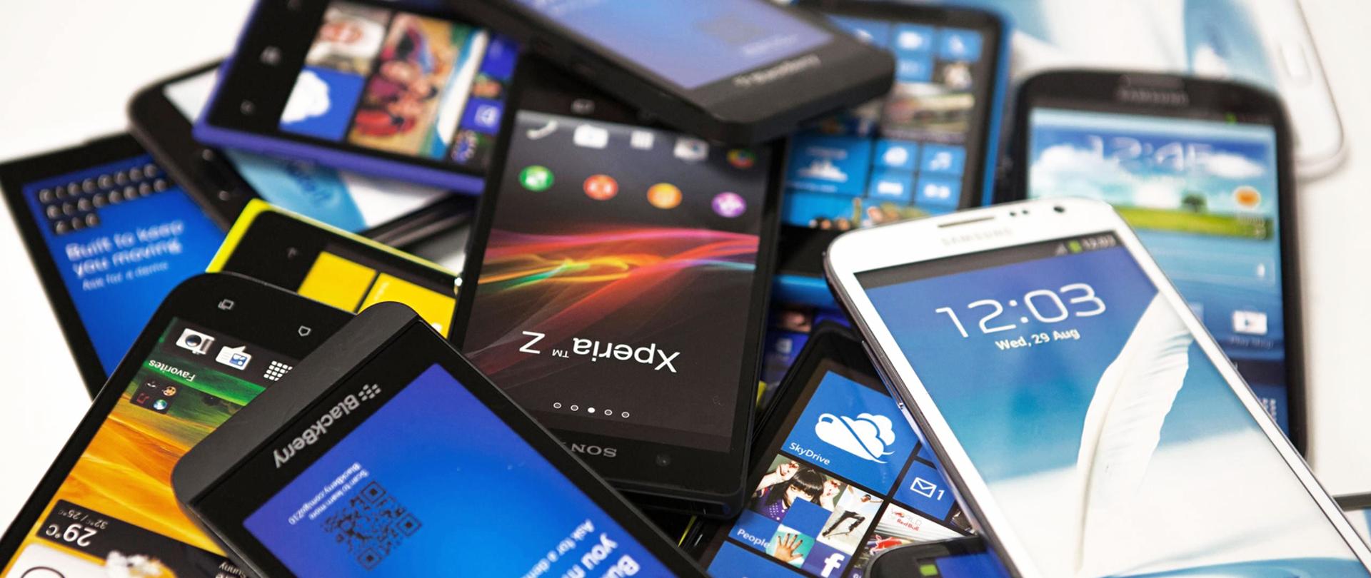 na zdjęciu widoczne telefony komórkowe, są włączone leżą jeden na drugim