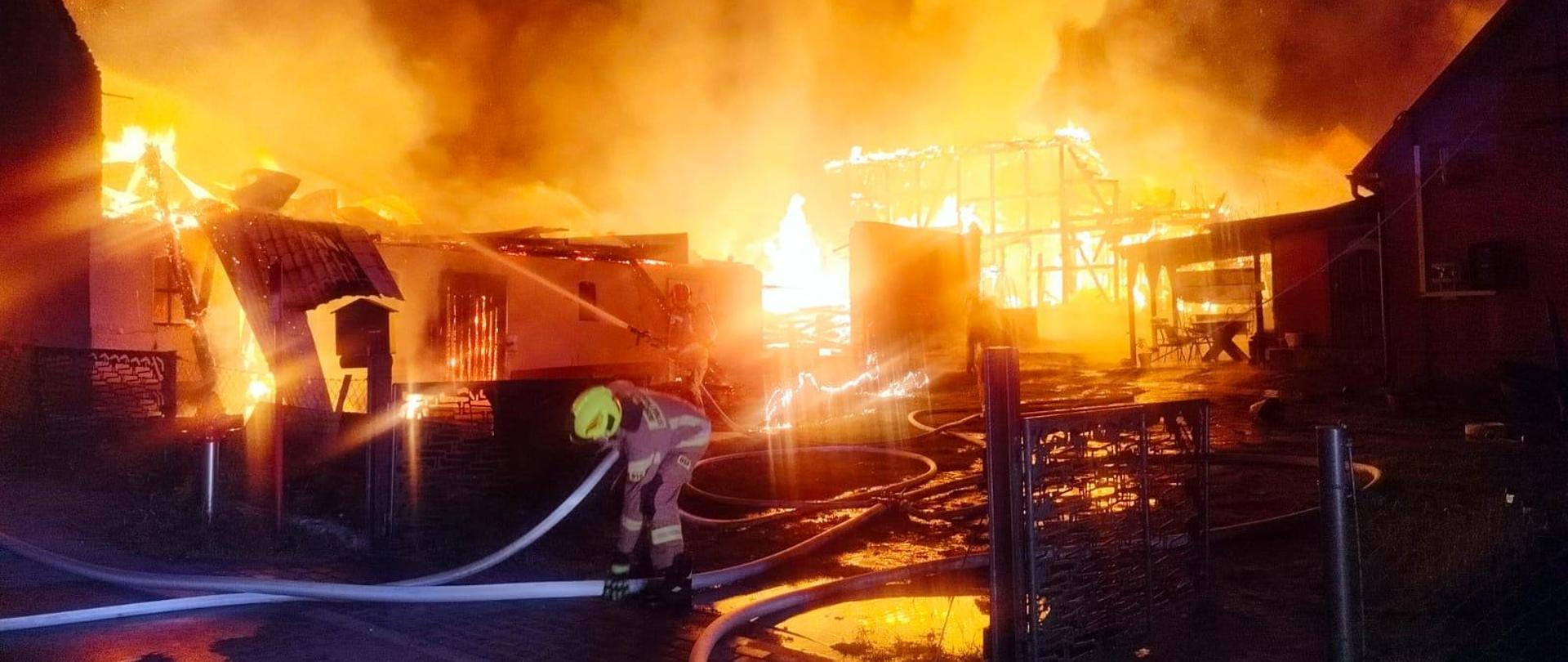 Zdjęcie palących się dwóch budynków gospodarczych w porze nocnej. Duże kłęby dymu o ognia