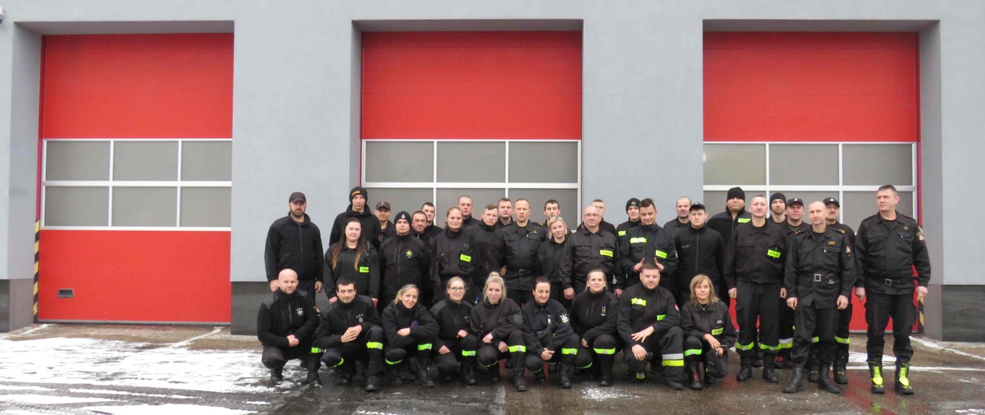 Grupa strażaków OSP stojąca przed budynkiem strażnicy.