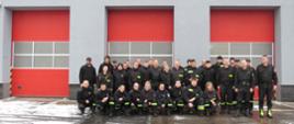 Grupa strażaków OSP stojąca przed budynkiem strażnicy.
