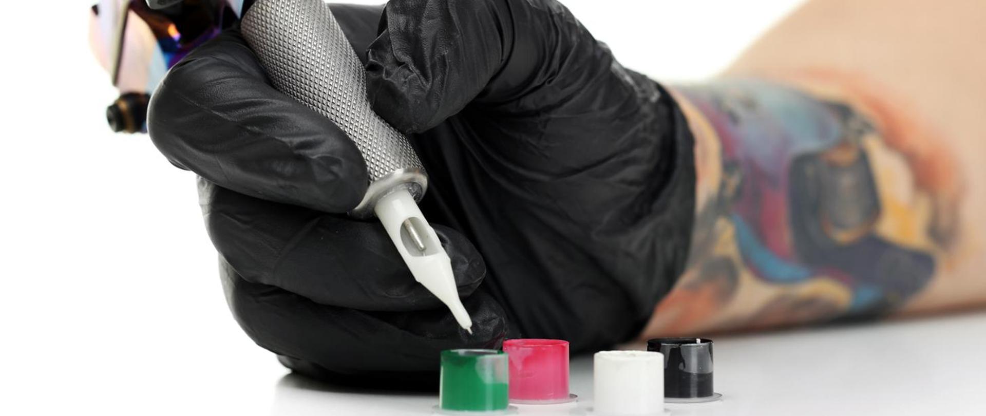 Na zdjęciu widzimy tatuażystę w trakcie pracy