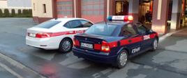 Zdjęcie przedstawia prawy bok nowego samochodu operacyjnego Komendy Powiatowej w Kluczborku i dotychczasowy samochód Opel Astra.