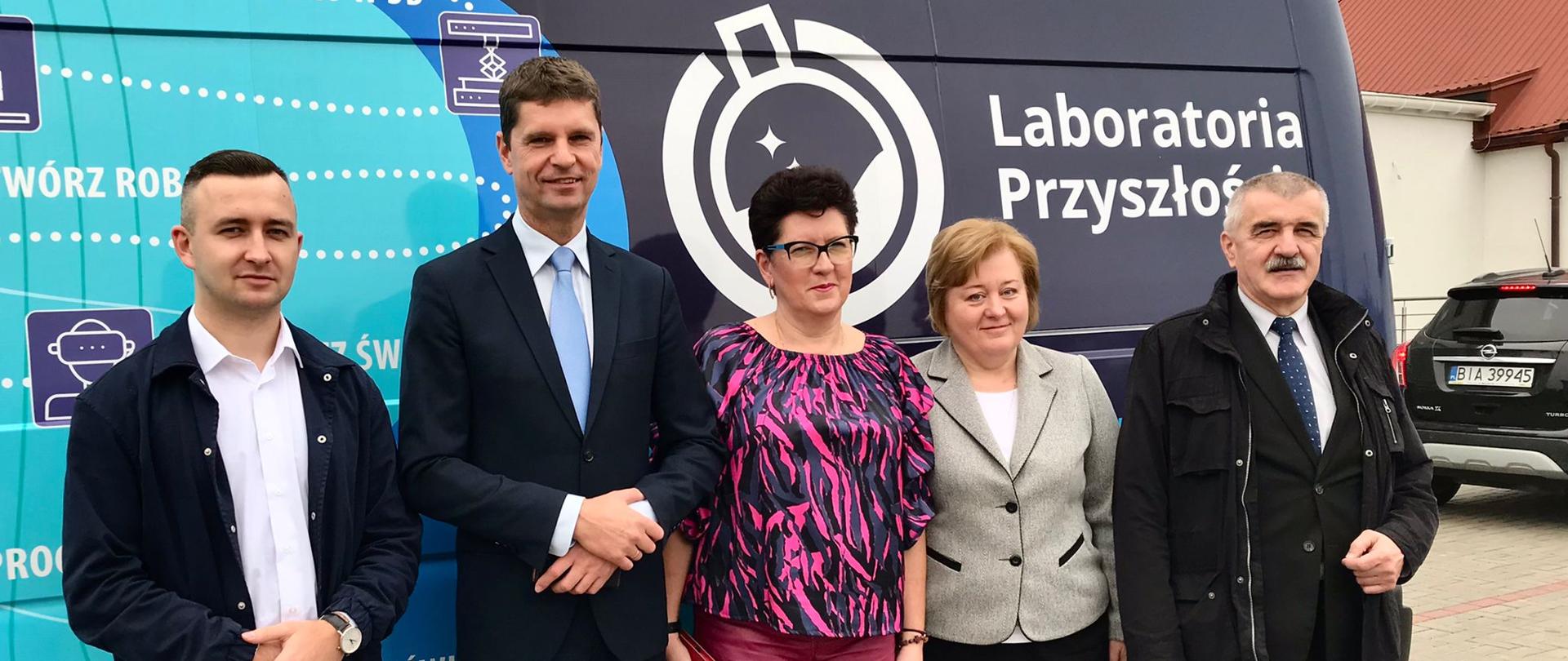 Wiceminister Piontkowski i cztery osoby stoją przy granatowej furgonetce, która ma na burcie napis Laboratoria Przyszłości.