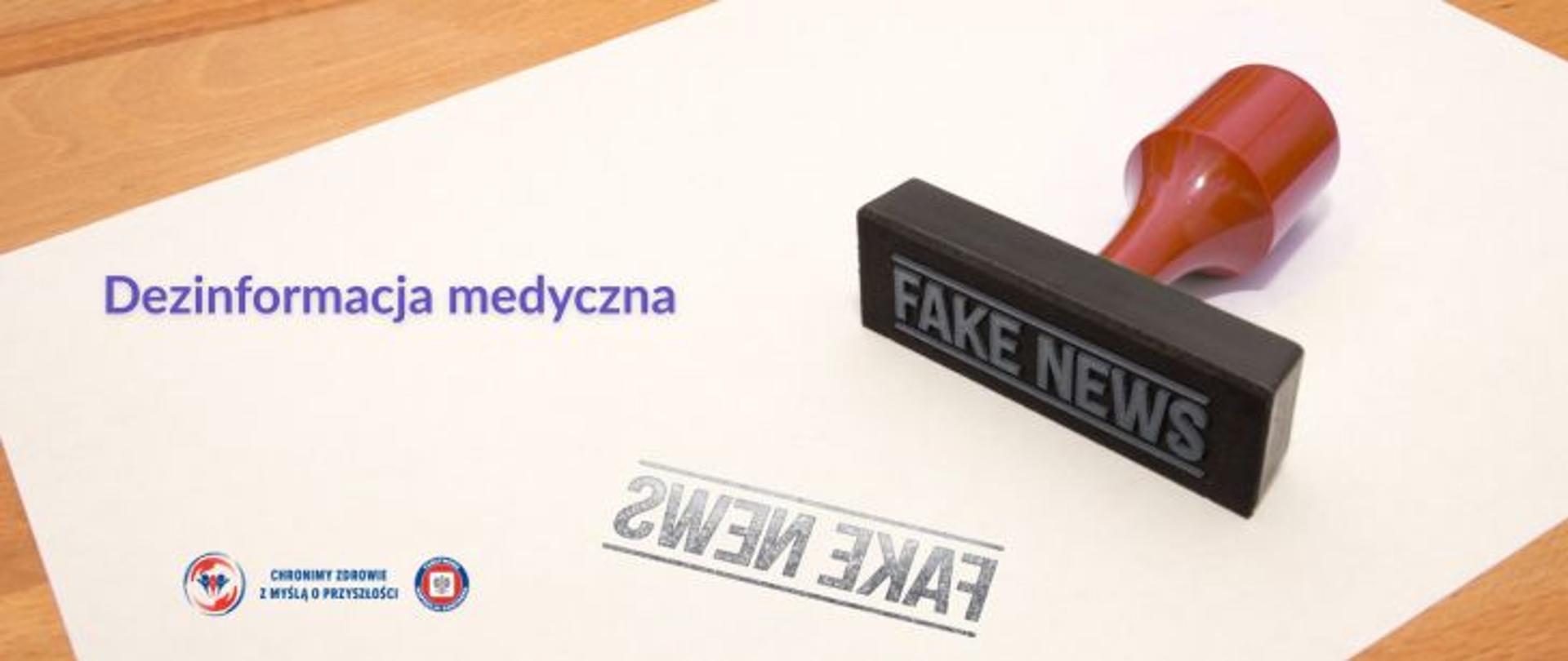Na brązowym blacie stołu biała kartka z prawej strony pieczątka w kolorze czarnym z czerwoną rączką. Na pieczątce napis FAKE NEWS. Na kartce odbity ciemny napis FAKE NEWS. W lewym górnym rogu fioletowy napis dezinformacja medyczna. W lewym dolnym rogu Logo Państwowej Inspekcji Sanitarnej wraz z hasłem: chronimy zdrowie z myślą o przyszłości. 
