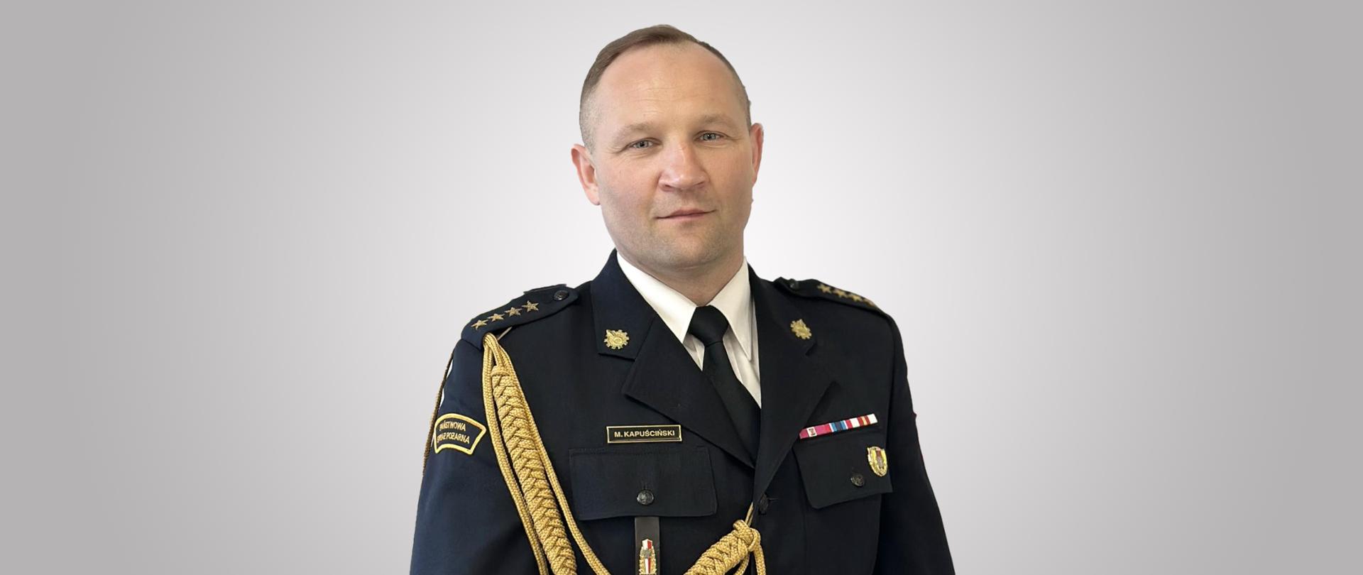 zdjęcie przedstawia starszego kapitana Marcina Kapuścińskiego w mundurze wyjściowym. Zdjęcie portretowe