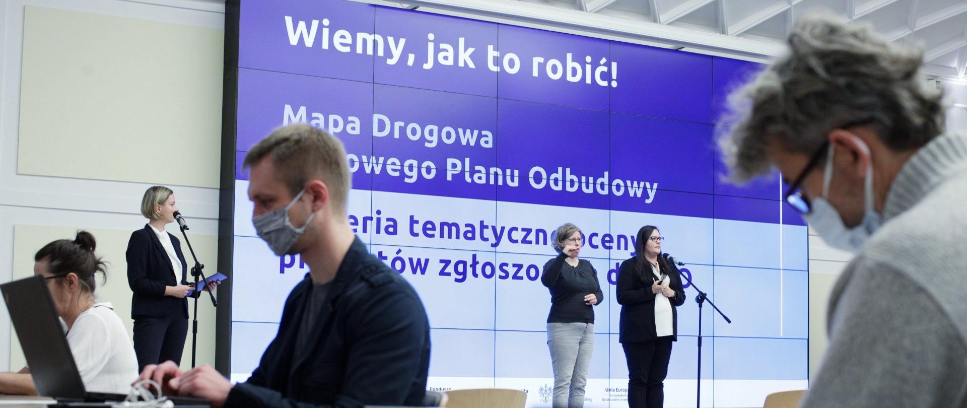 Na zdjęciu minister Małgorzata Jarosińska-Jedynak i uczestnicy konferencji dotyczącej Krajowego Planu Odbudowy, jasne tło.