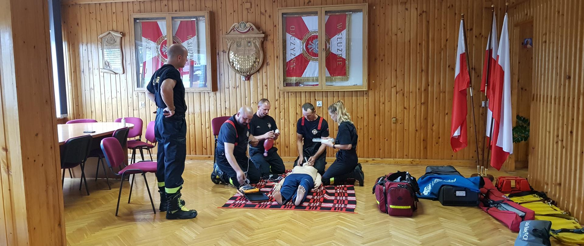 druhowie OSP z powiatu kozienickiego w trakcie egzaminu praktycznego z KPP wraz z egzaminatorem na świetlicy KP PSP Kozienice