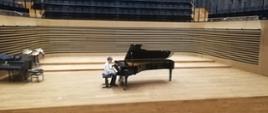Uczeń grający na fortepianie na scenie sali koncertowej PSM