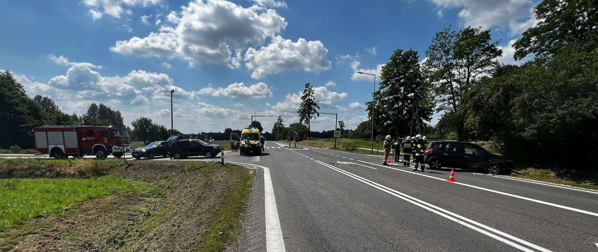 Zdjęcie przedstawia uszkodzony pojazd. Z prawej strażacy.