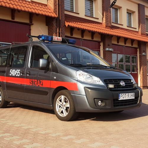 Na zdjęciu samochód specjalny typu Mikrobus na placu manewrowym przed garażami Jednostki Ratowniczo-Gaśniczej