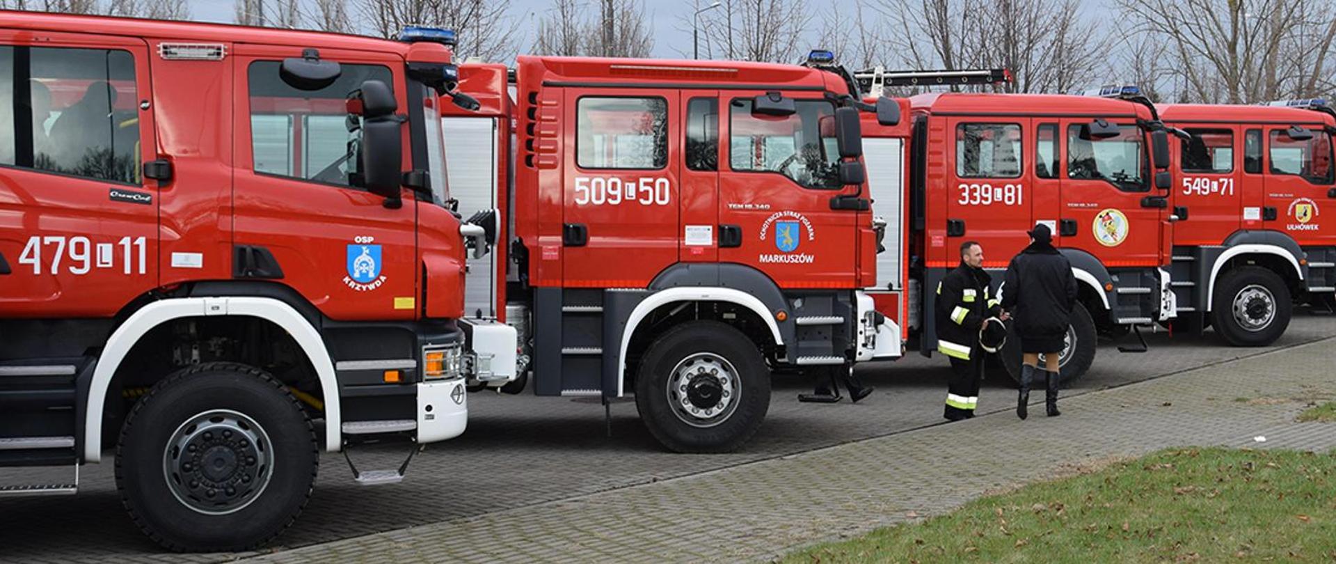 Zdjęcie przedstawia cztery samochody pożarnicze ustawione na placu do przekazania dla jednostek OSP.