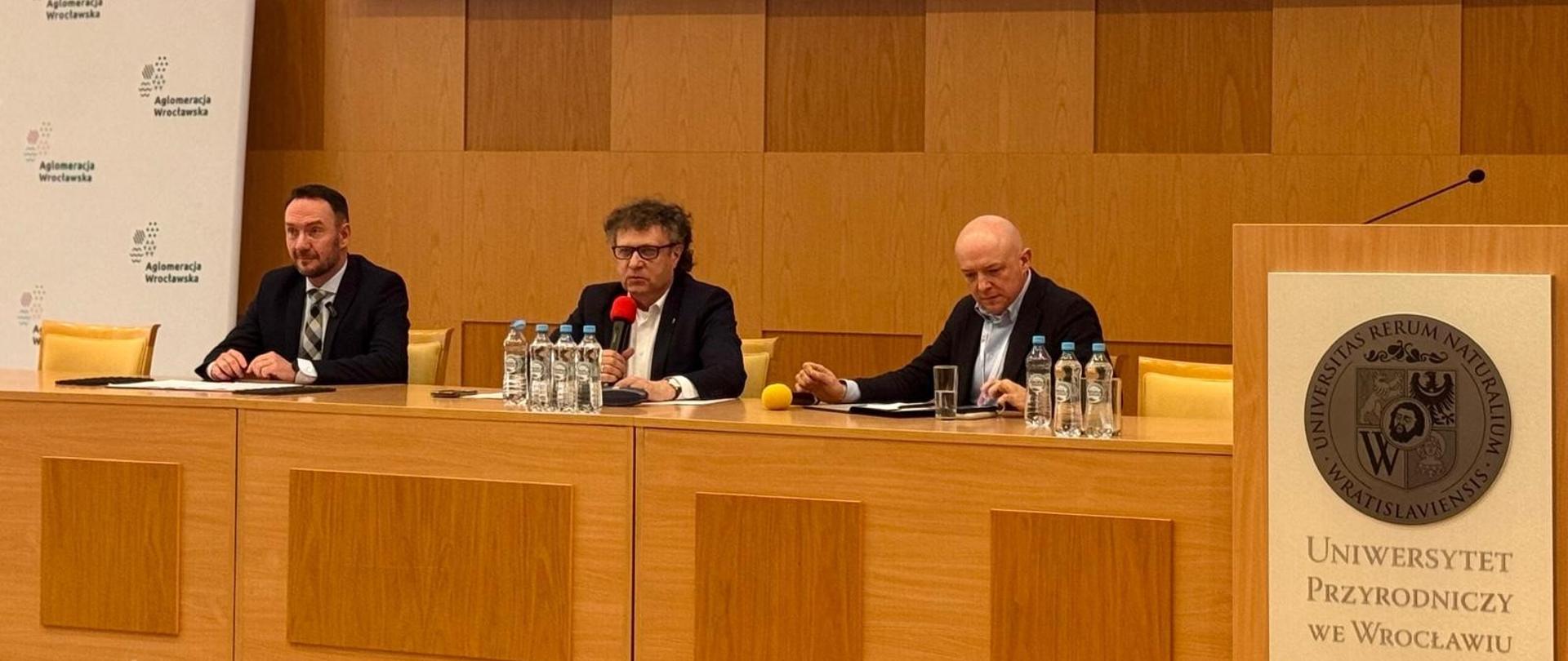 Wiceminister Jacek Karnowski siedzi w środku przy drewnianym stole.