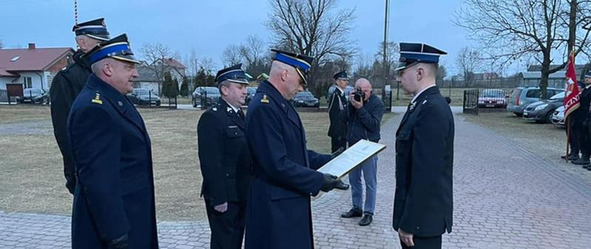 Przekazania decyzji podczas uroczystego apelu dokonał Zastępca Świętokrzyskiego Komendanta Wojewódzkiego PSP st. bryg. Grzegorz Rajca w asyście Komendanta Powiatowego PSP w Staszowie st. bryg. Rafała Gajewicza, Burmistrza Miasta i Gminy Staszów Leszka Kopcia oraz Komendanta Miejsko Gminnego ZOSP RP w Staszowie druha Grzegorza Kwietniewskiego