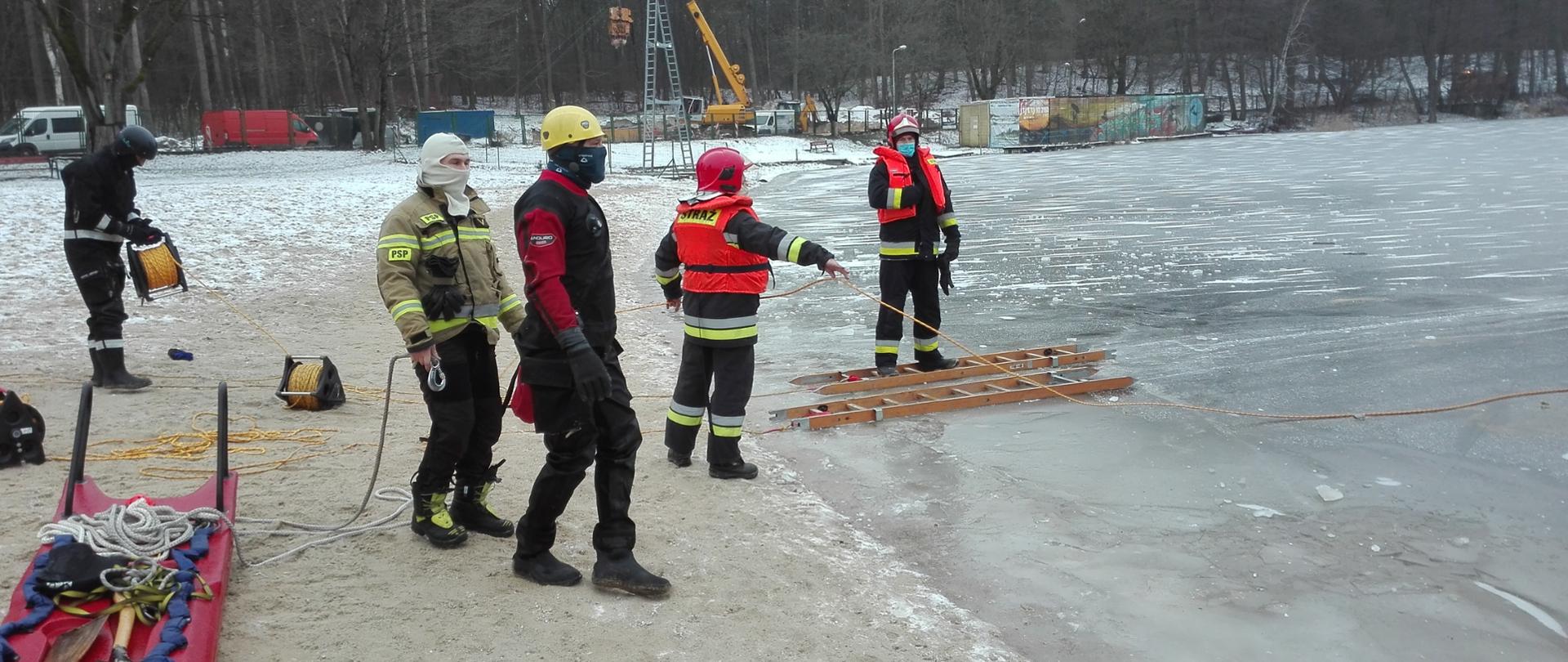 Ratownicy ćwiczący na brzegu zamarzniętego jeziora