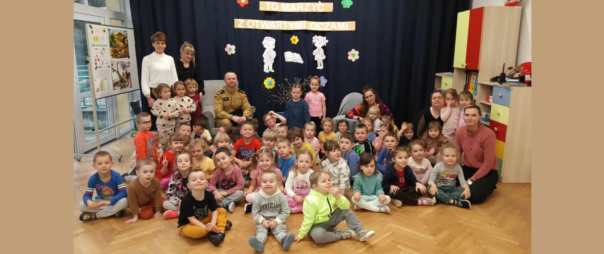 Zdjęcie grupowe dzieci z przedszkola w Chocianowie wraz z opiekunkami i strażakiem PSP