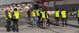 Kilkunastoosobowa grupa ekspertów ds. Seveso z państw członkowskich Unii Europejskiej oraz dwoje przedstawicieli Wojewódzkiego Inspektoratu Ochrony Środowiska odbywa wizytę studyjną w SOUDAL Manufacturing sp. z o.o. w Pionkach. W tle widać jednopiętrowy budynek zakładu.