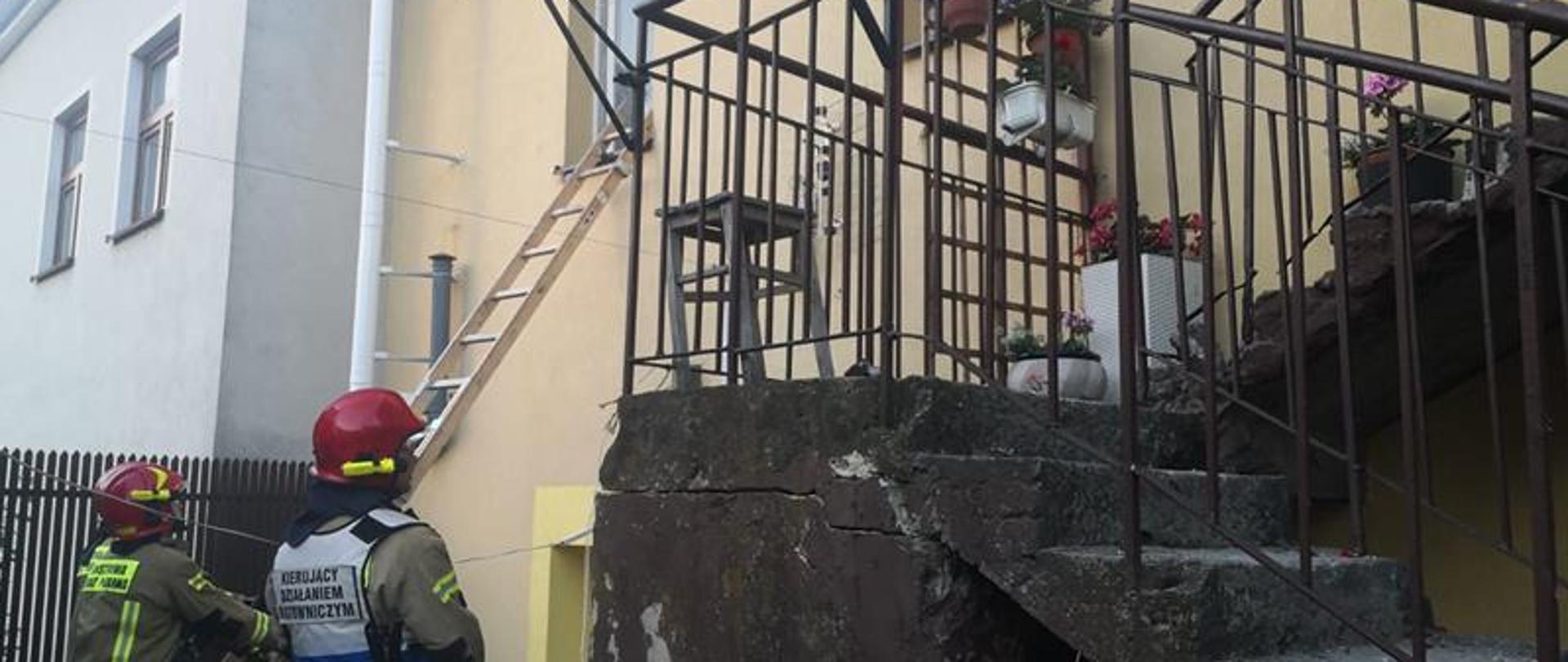 Do okna pomieszczenia które jest zniszczone przez wybuch sprawiona jest drabina nasadkowa. Kierujący Działaniem Ratowniczym nadzoruje ewakuacje mienia. po drabinie.