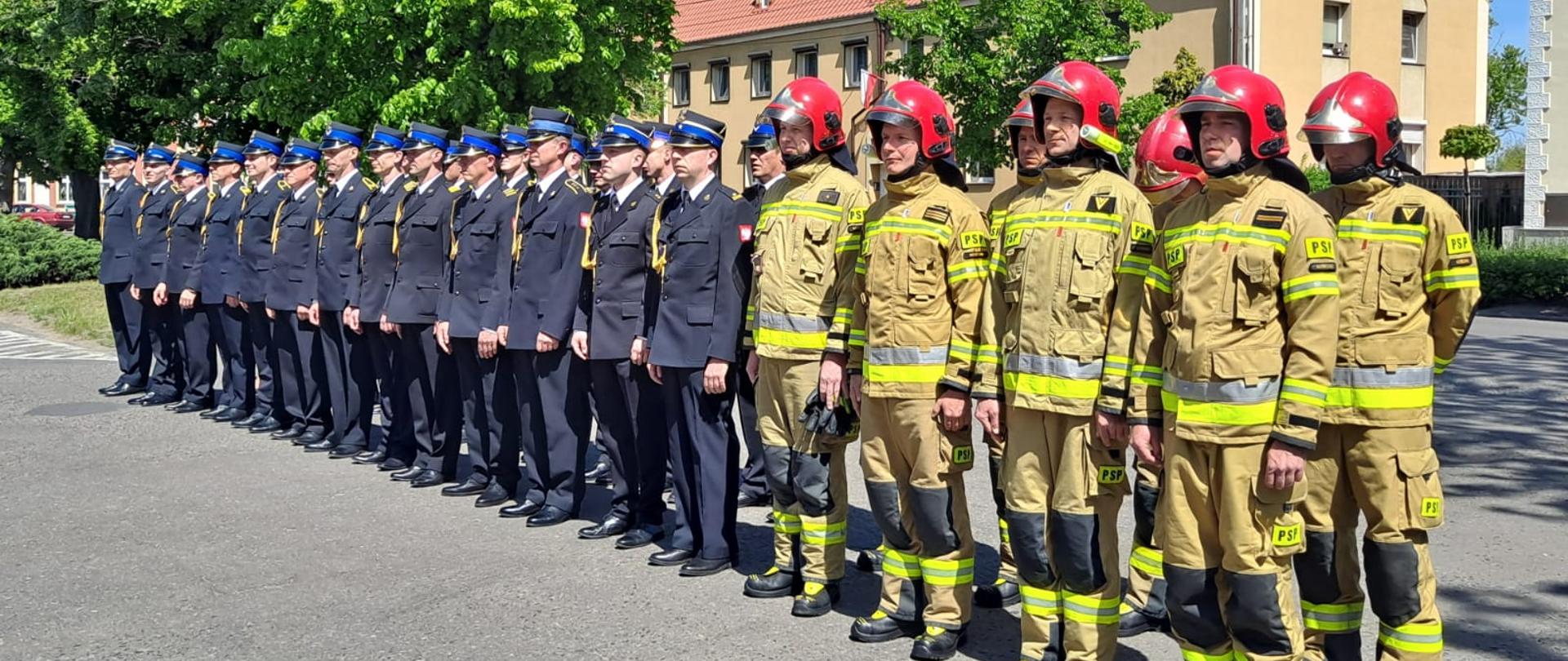DZIEŃ STRAŻAKA W KOŚCIAŃSKIEJ KOMENDZIE. Strażacy biorą udział w uroczystym apelu z okazji Dnia Strażaka. Uroczystość ma miejsce przed budynkiem strażnicy. 