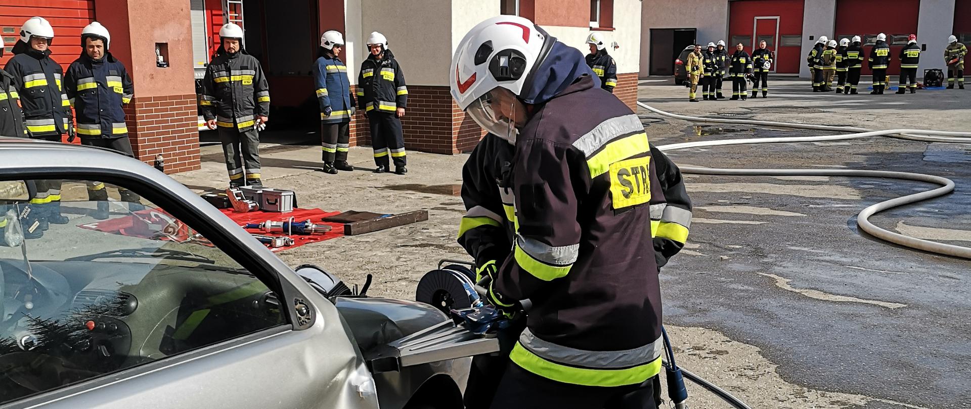Egzamin praktyczny - strażacy OSP wykonują dostęp do uwięzionej osoby we wraku samochodu