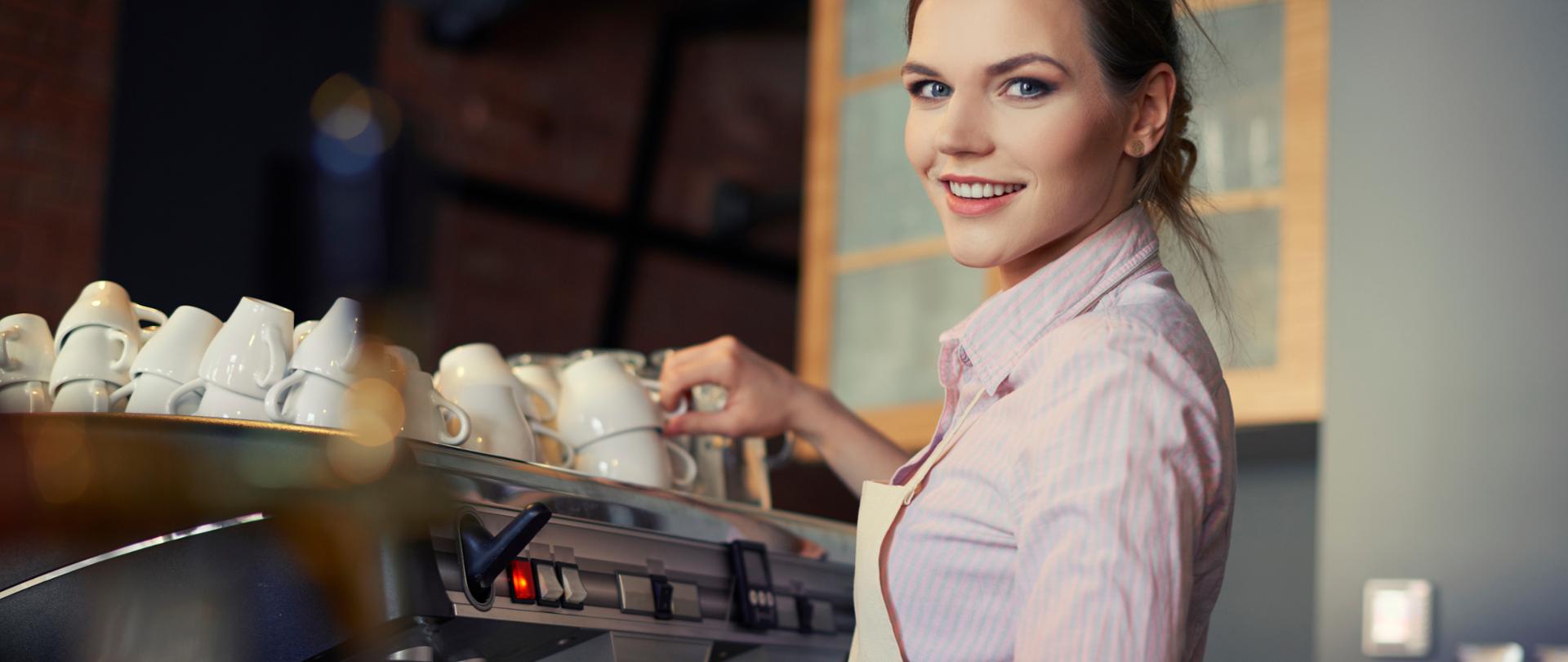 Portret baristki robiącej kawę przy ekspresie.