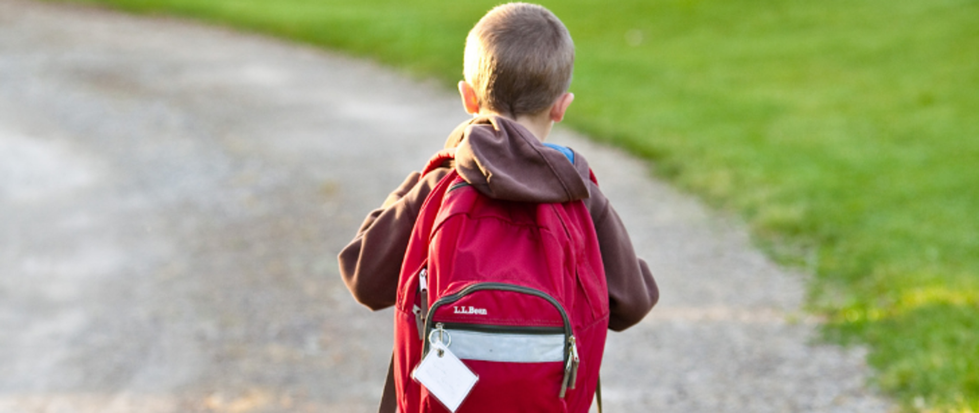 Dziecko z plecakiem idące drogą