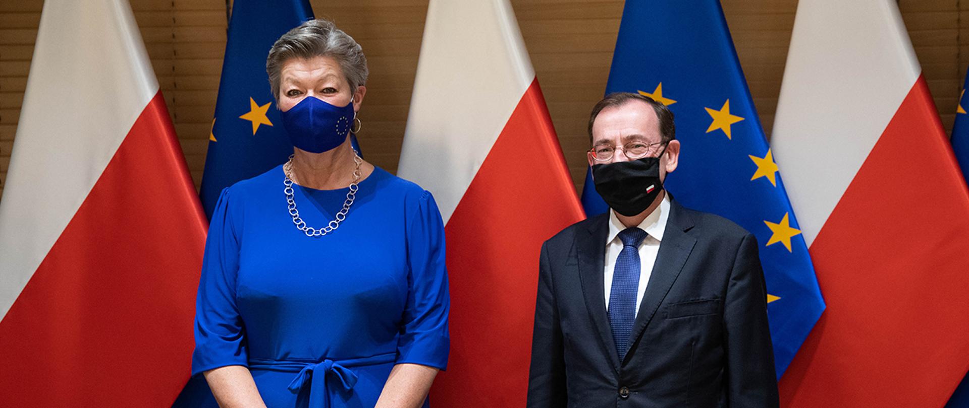 Minister Mariusz Kamiński oraz Ylva Johansson – unijna Komisarz do Spraw Wewnętrznych na tle flag Polski i Unii Europejskiej.
