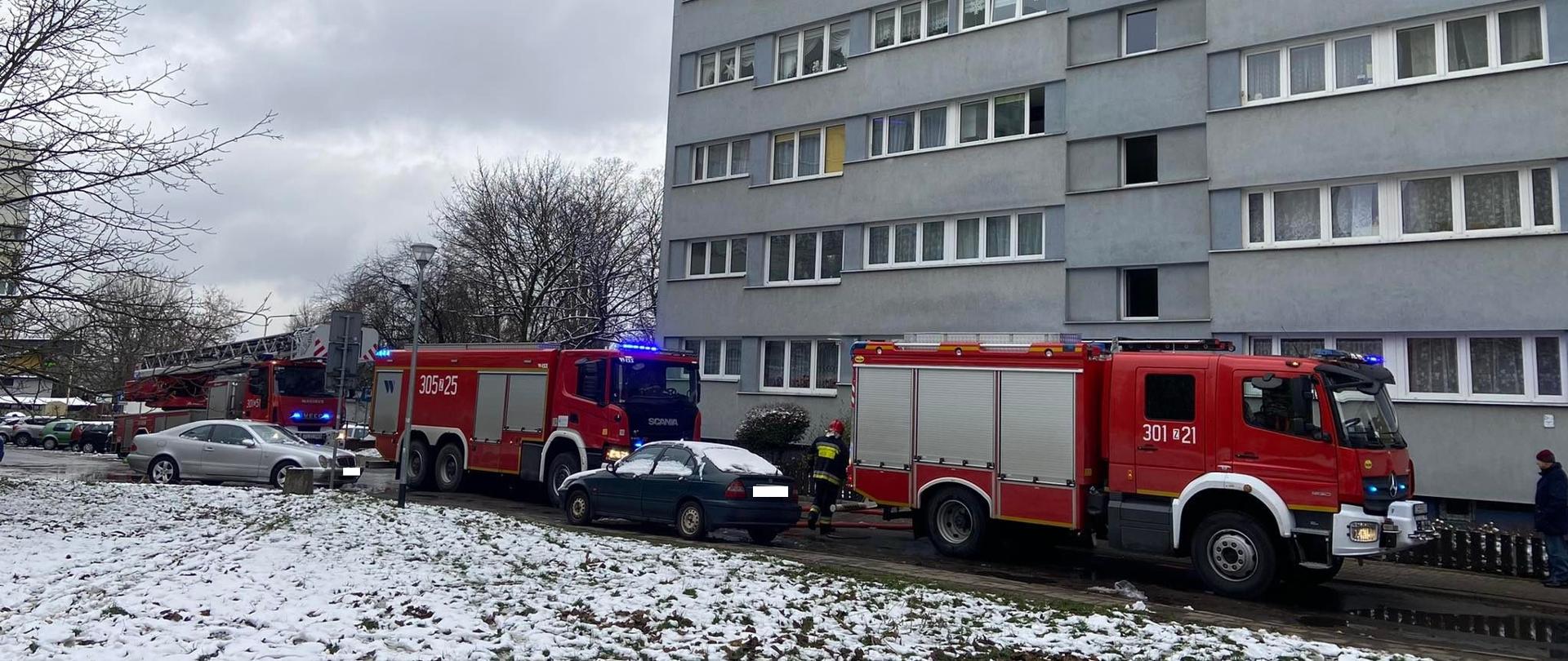 Trzy wozy strażackie z drabiną mechaniczną włącznie stojące przed blokiem przy ulicy 26 Kwietnia, rozwinięta linia gaśnicza W-75