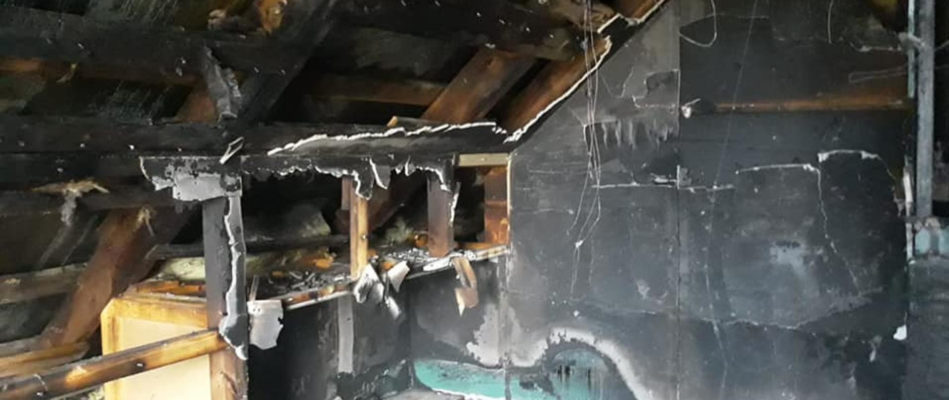 Widoczne miejsce zdarzenia, pomieszczenie na poddaszu zniszczone na skutek pożaru widoczna nadpalona konstrukcja dachu.