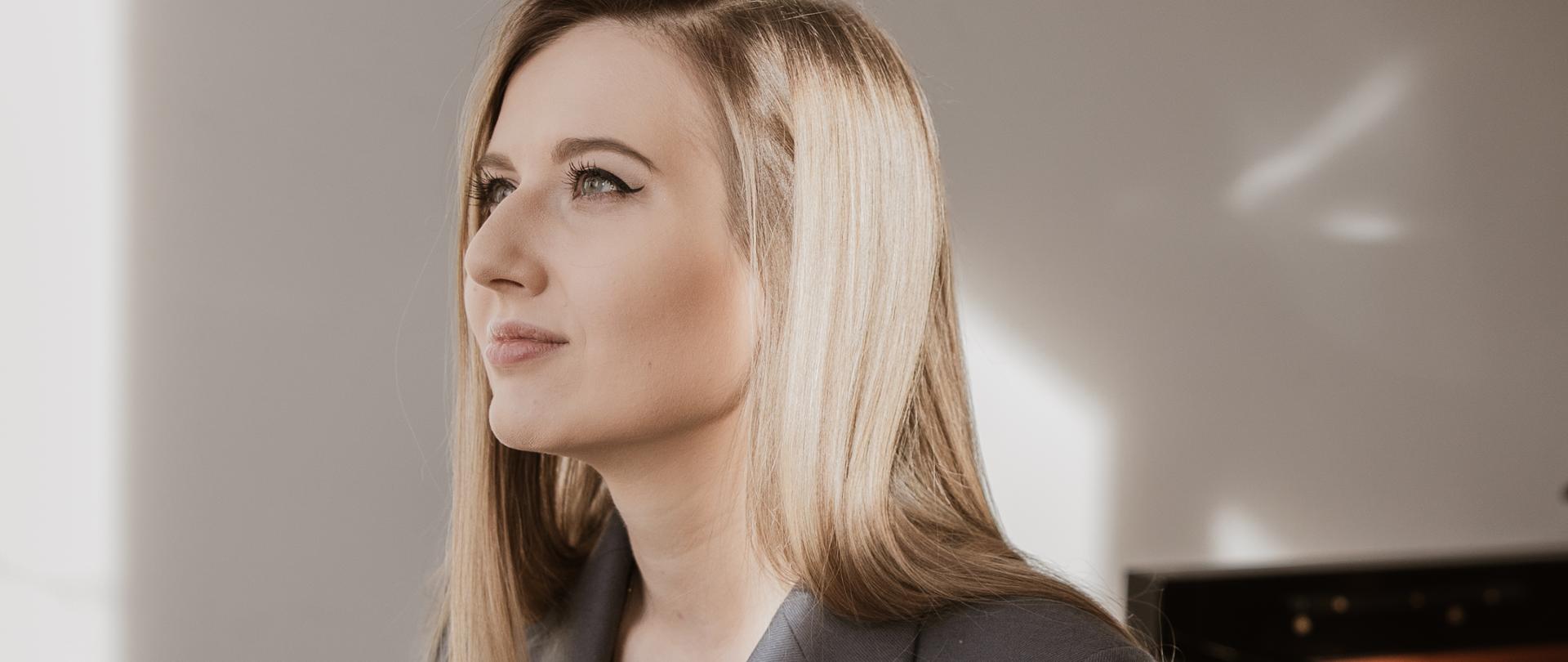 Postać kobiety przy fortepianie.